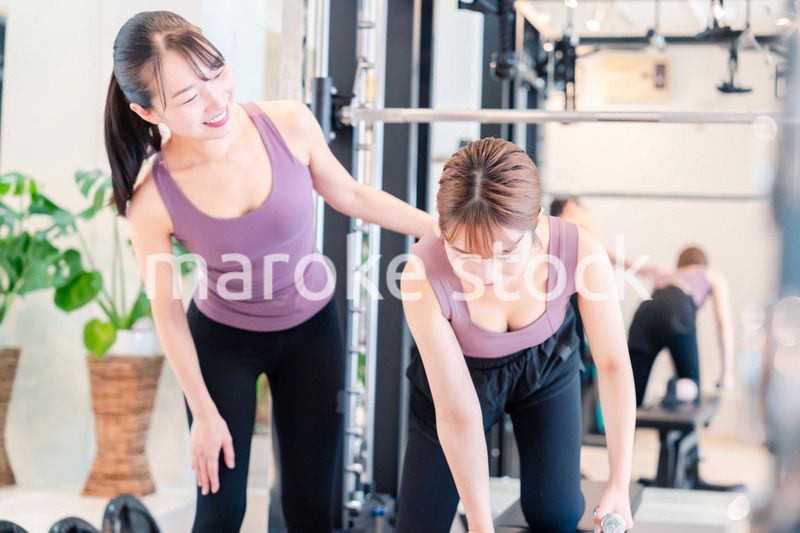 ジムで女性コーチのパーソナルトレーニングを受ける女性