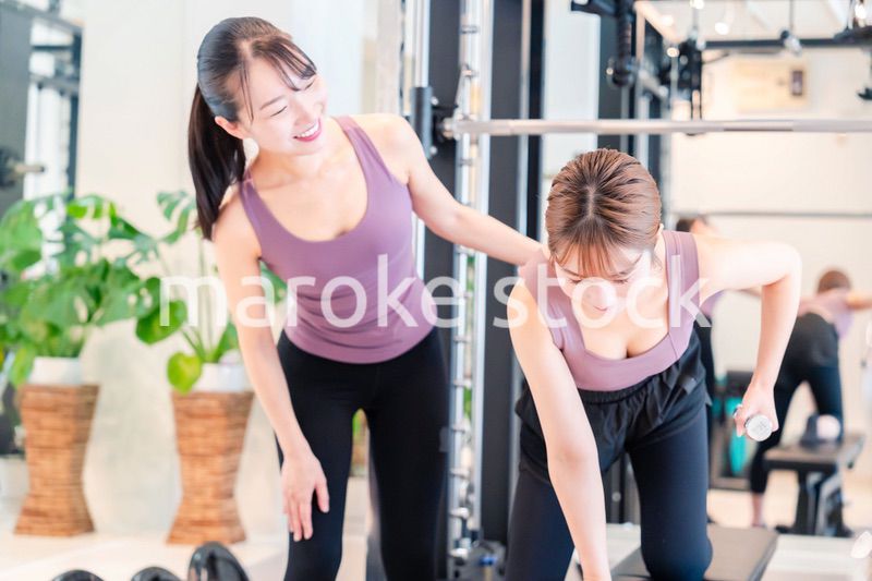 ジムで女性コーチのパーソナルトレーニングを受ける女性