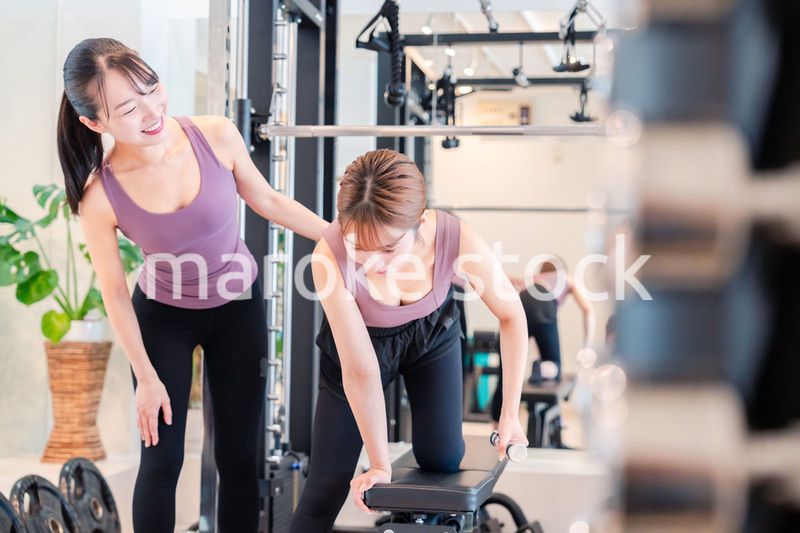 ジムで女性コーチのパーソナルトレーニングを受ける女性