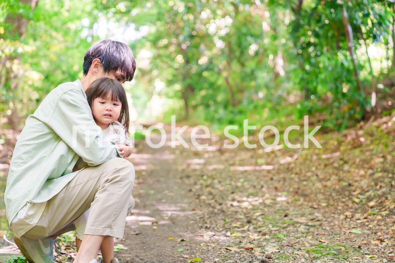 涙を流す小さな女の子を抱っこするパパ