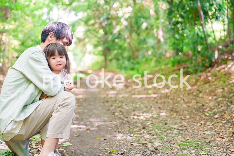 涙を流す小さな女の子を抱っこするパパ