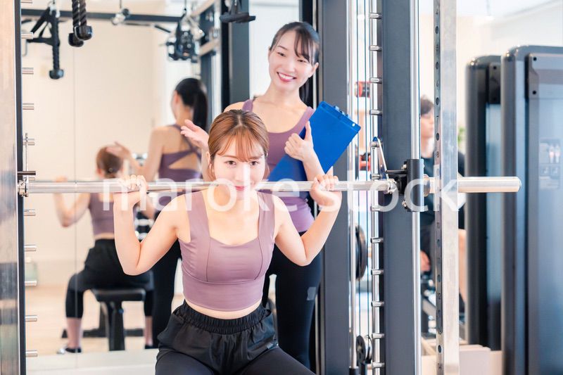 ジムで女性コーチのパーソナルトレーニングを受ける女性