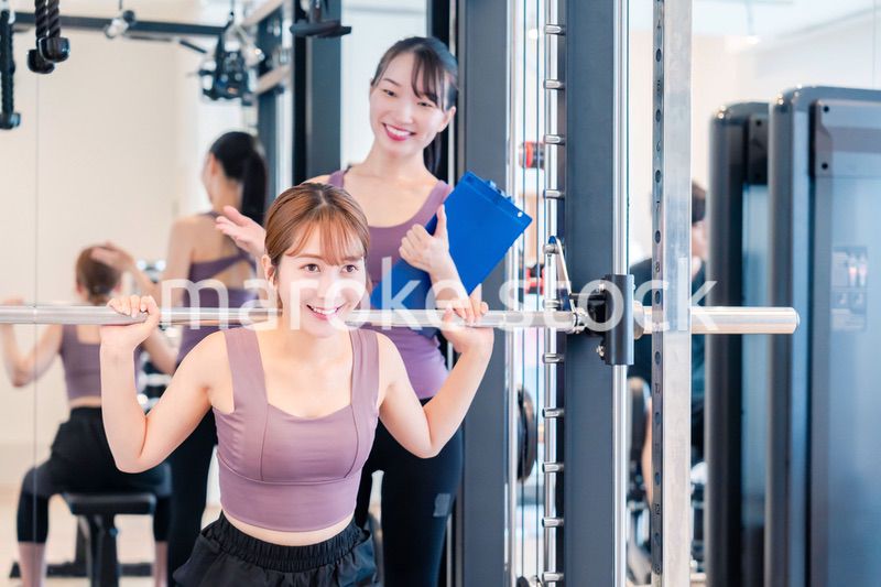 ジムで女性コーチのパーソナルトレーニングを受ける女性