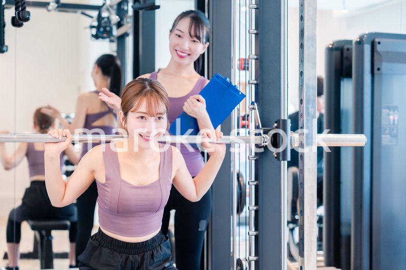 ジムで女性コーチのパーソナルトレーニングを受ける女性