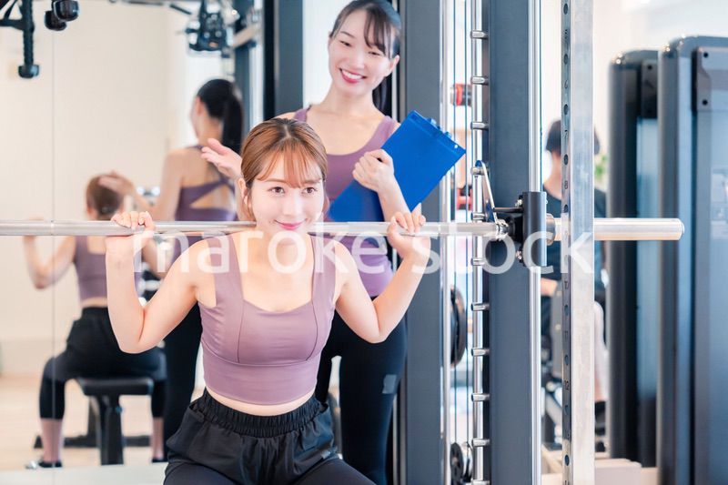 ジムで女性コーチのパーソナルトレーニングを受ける女性