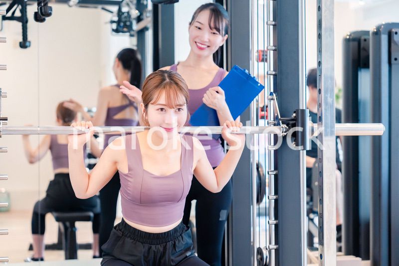 ジムで女性コーチのパーソナルトレーニングを受ける女性
