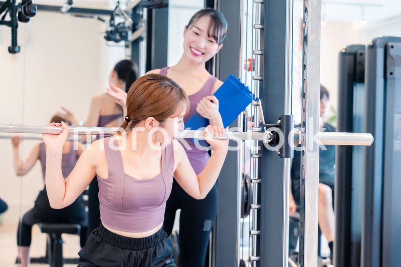 ジムで女性コーチのパーソナルトレーニングを受ける女性