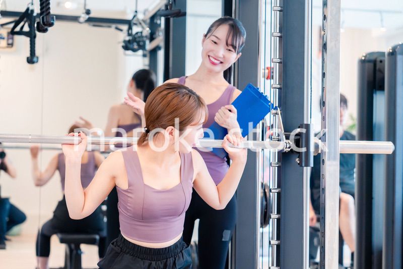 ジムで女性コーチのパーソナルトレーニングを受ける女性