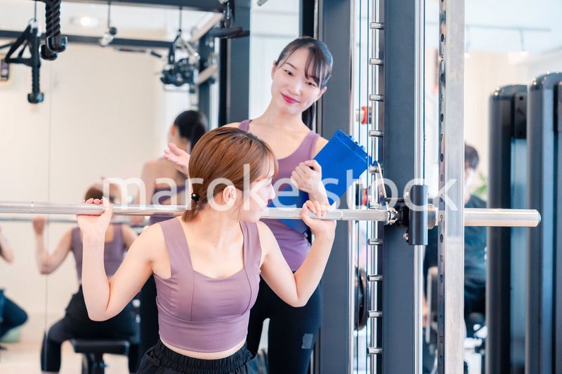 ジムで女性コーチのパーソナルトレーニングを受ける女性
