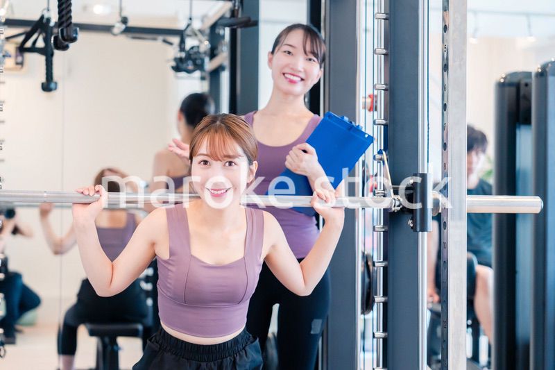 ジムで女性コーチのパーソナルトレーニングを受ける女性