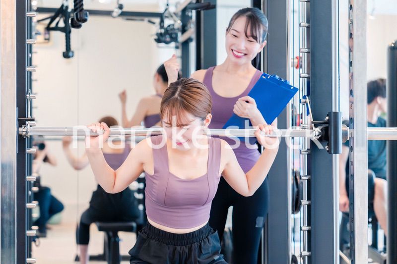ジムで女性コーチのパーソナルトレーニングを受ける女性