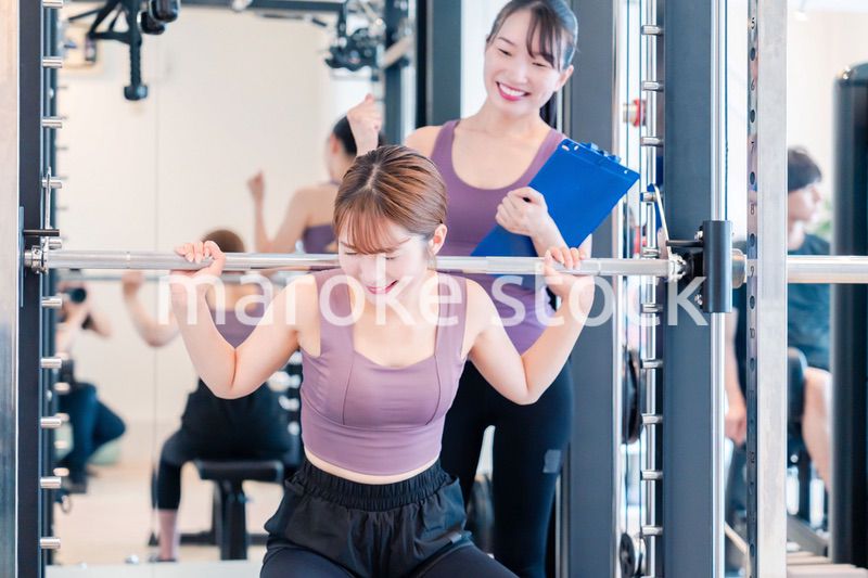 ジムで女性コーチのパーソナルトレーニングを受ける女性