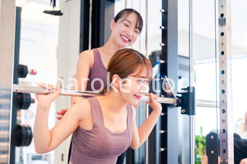 女性トレーナーからの指導を受けて筋トレをする女性