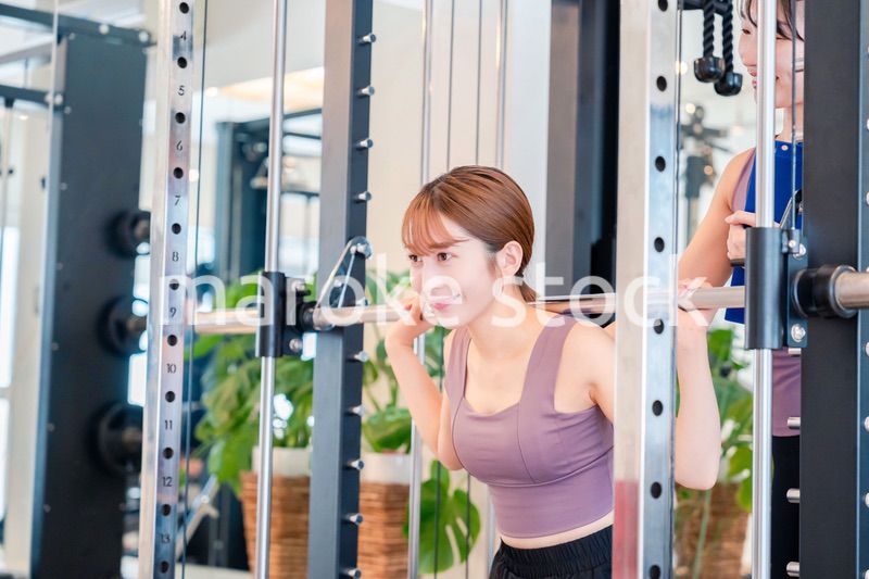 女性トレーナーからの指導を受けて筋トレをする女性