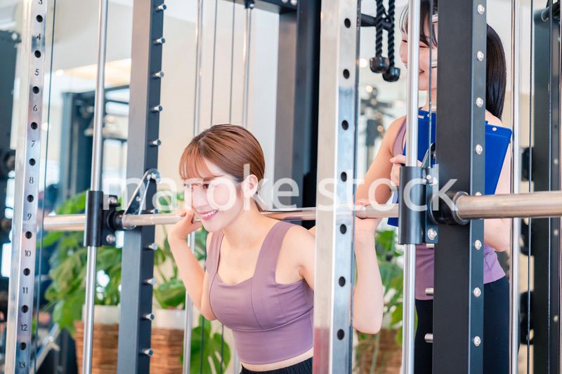 女性トレーナーからの指導を受けて筋トレをする女性