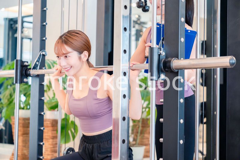 女性トレーナーからの指導を受けて筋トレをする女性