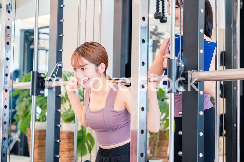 女性トレーナーからの指導を受けて筋トレをする女性