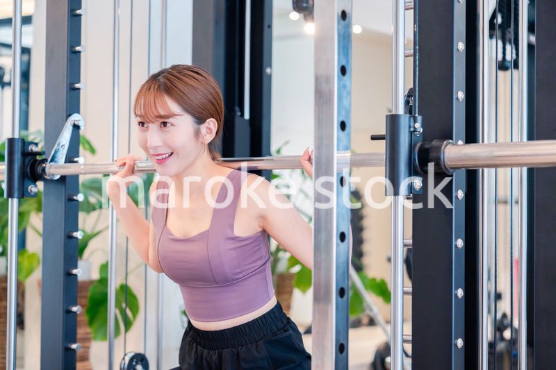 ジムで筋トレをするスポーティーな若い女性