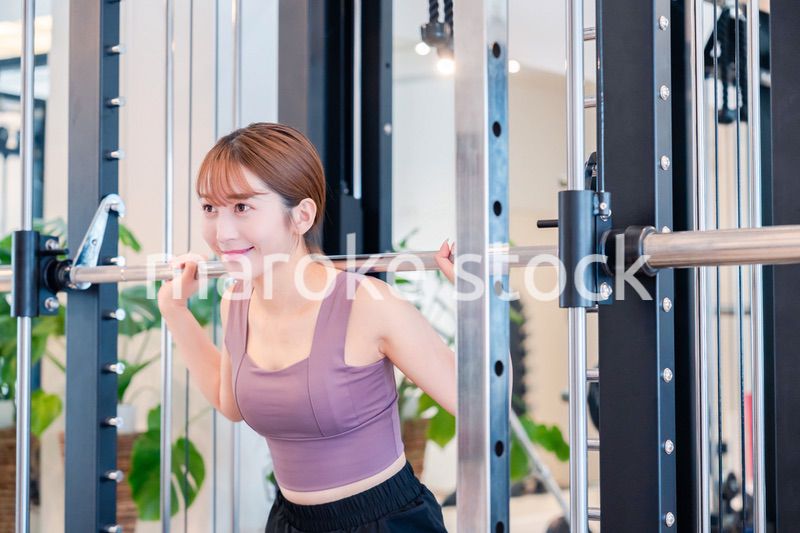 ジムで筋トレをするスポーティーな若い女性