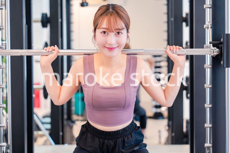 ジムで筋トレをするスポーティーな若い女性