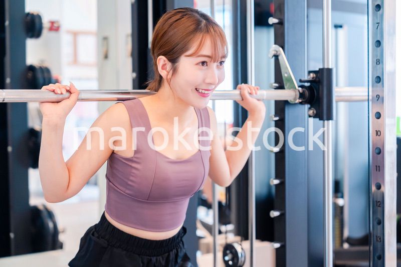 ジムで筋トレをするスポーティーな若い女性