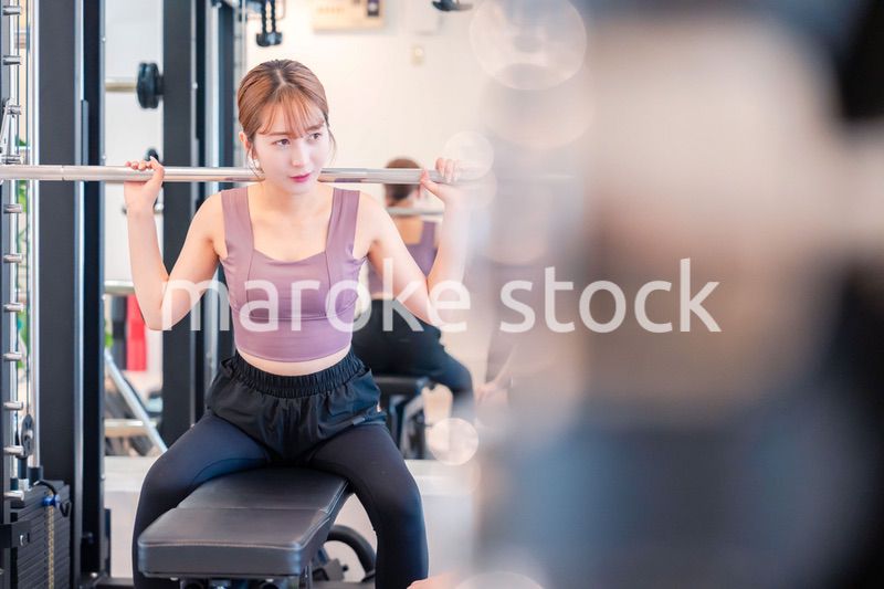 ジムで筋トレをするスポーティーな若い女性