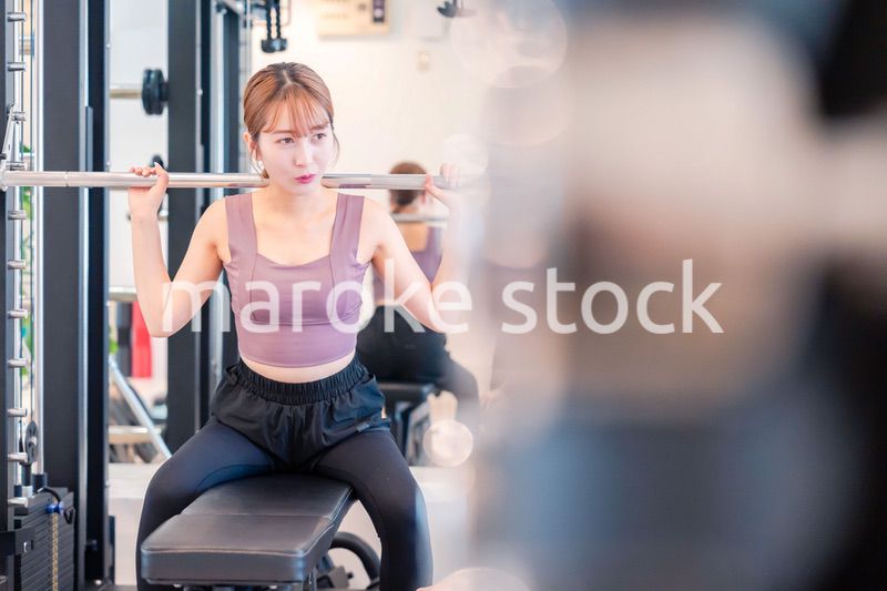 ジムで筋トレをするスポーティーな若い女性