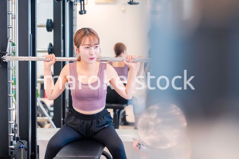 ジムで筋トレをするスポーティーな若い女性