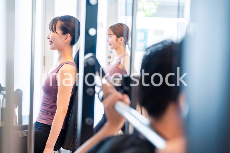 ジムのマシーンでトレーニングをする人