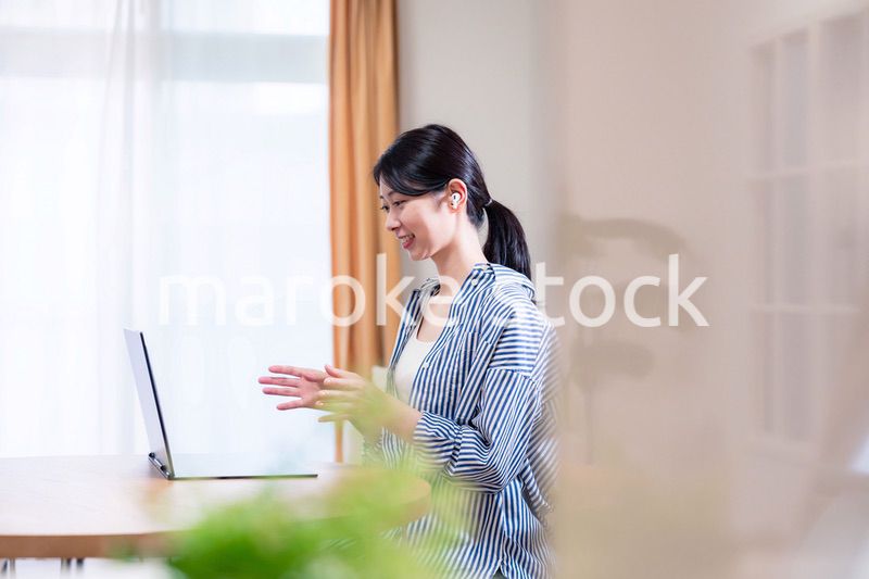 在宅でリモート会議に参加する若い女性社員