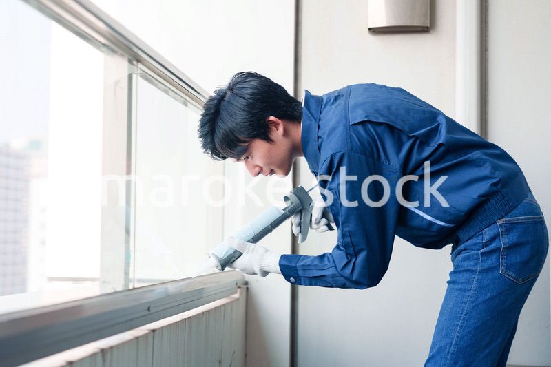 外装工事でコーキング材を塗る作業員の男性