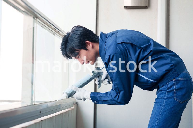 外装工事でコーキング材を塗る作業員の男性