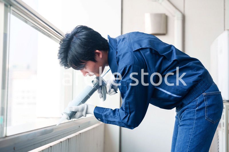 外装工事でコーキング材を塗る作業員の男性