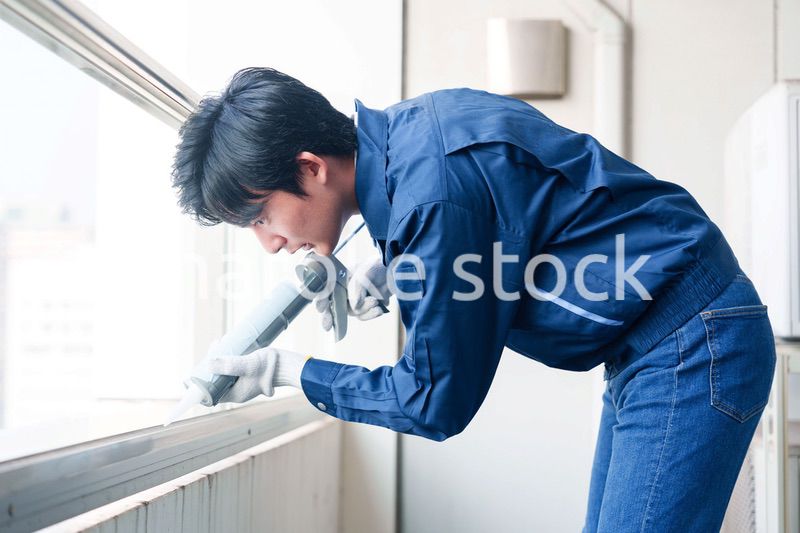 外装工事でコーキング材を塗る作業員の男性