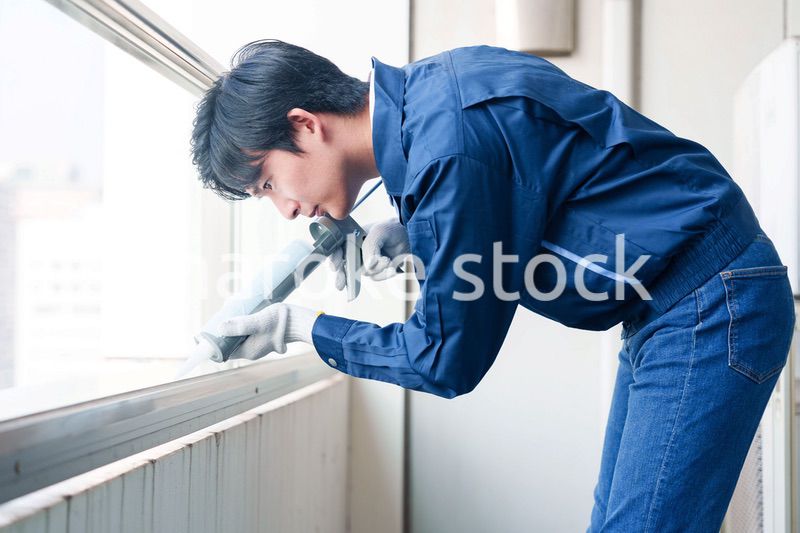 外装工事でコーキング材を塗る作業員の男性