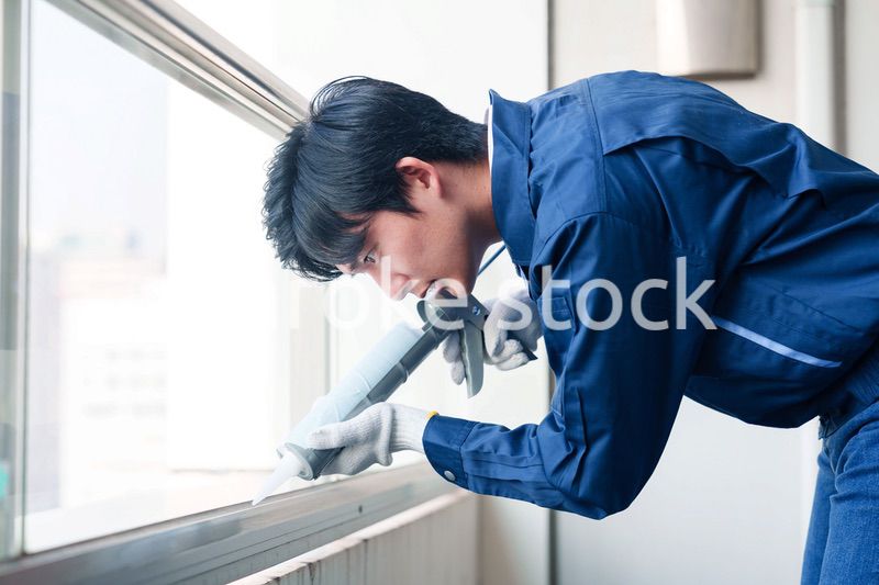 外装工事でコーキング材を塗る作業員の男性