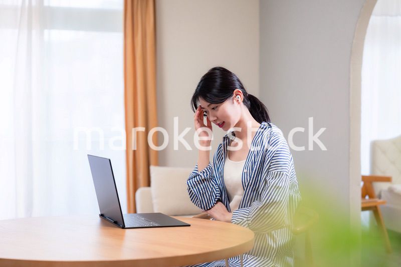 在宅勤務をしながら頭を抱える若い女性