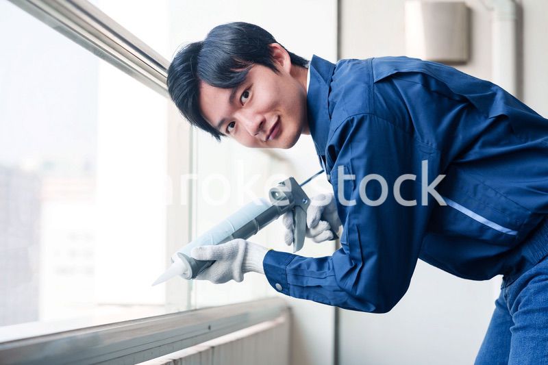 外装工事でコーキング材を塗る作業員の男性