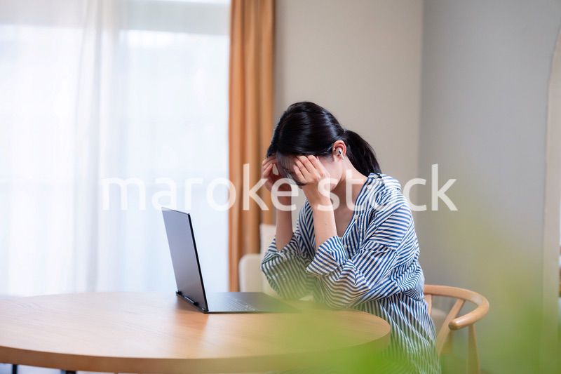 在宅勤務をしながら頭を抱える若い女性