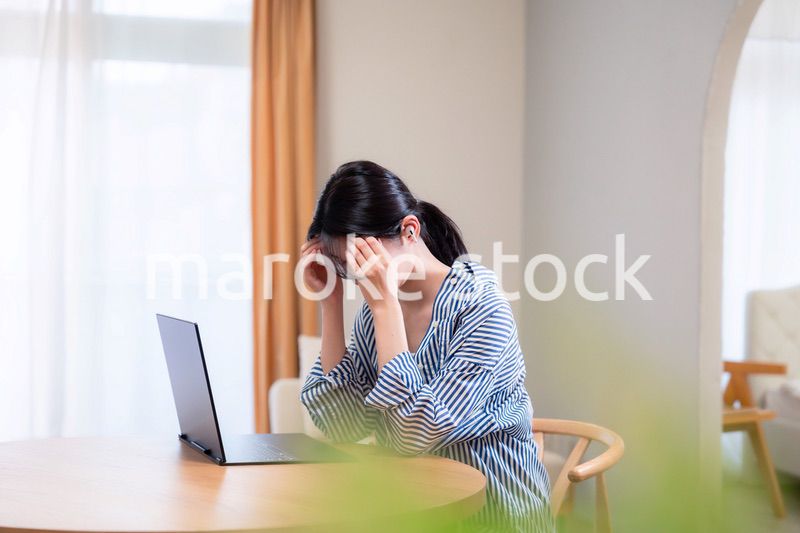 在宅勤務をしながら頭を抱える若い女性