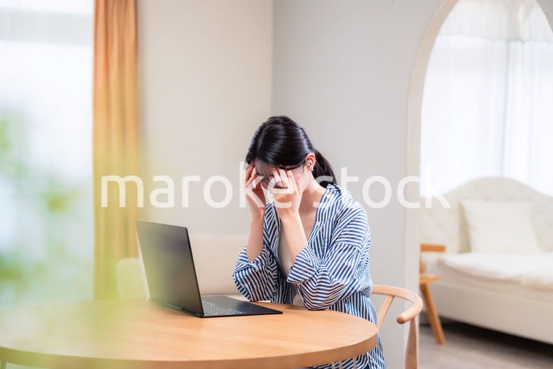 在宅勤務をしながら頭を抱える若い女性