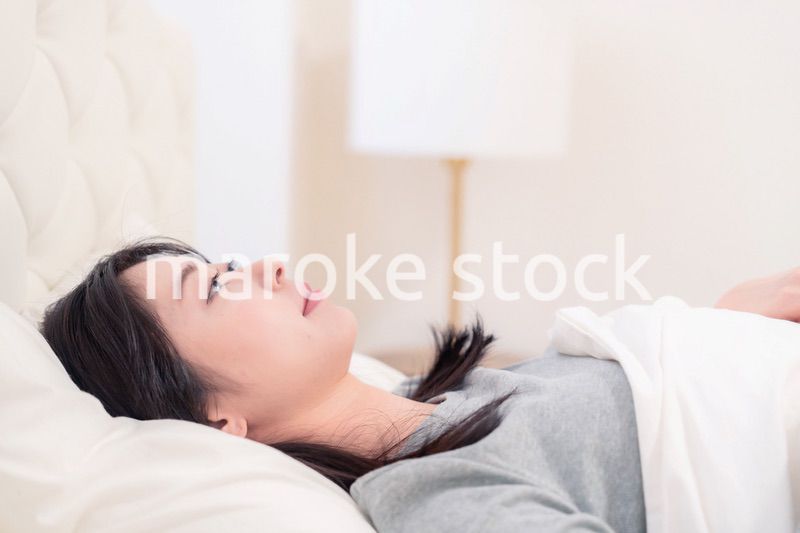 ベッドで寝る若い女性