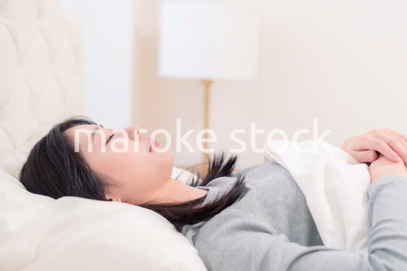 ベッドで寝る若い女性