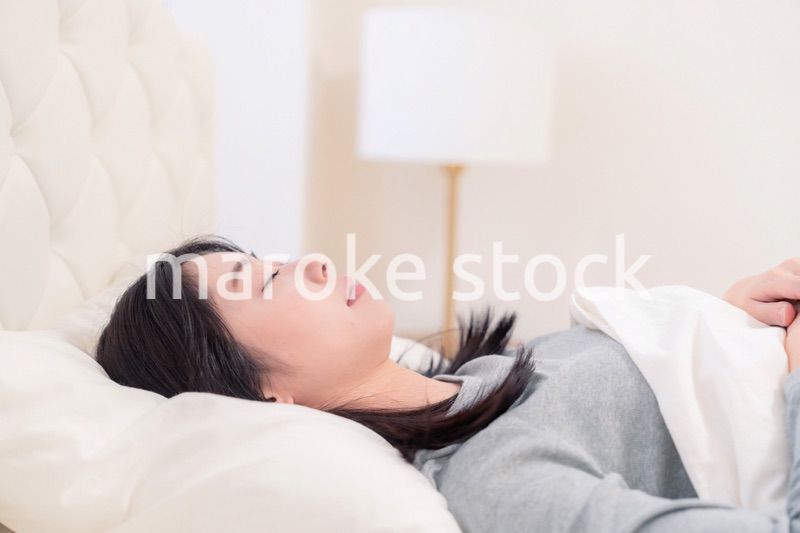 ベッドで寝る若い女性