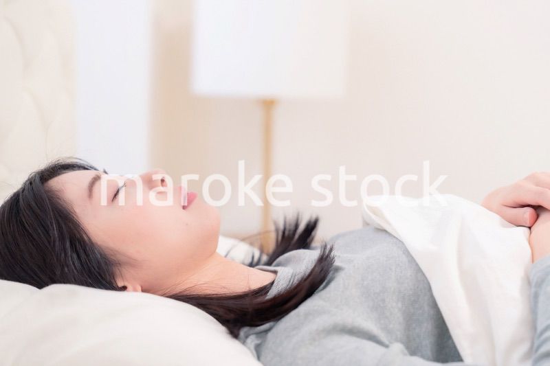 ベッドで寝る若い女性