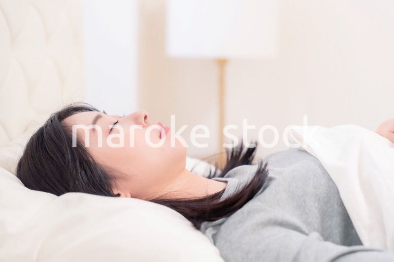 ベッドで寝る若い女性