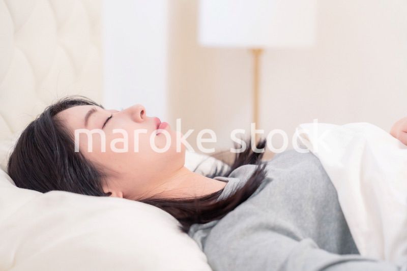ベッドで寝る若い女性