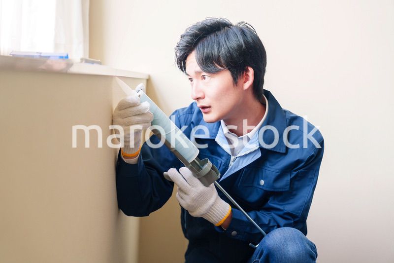 窓にコーキング材を塗る男性の作業員