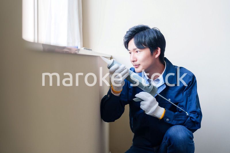 窓にコーキング材を塗る男性の作業員