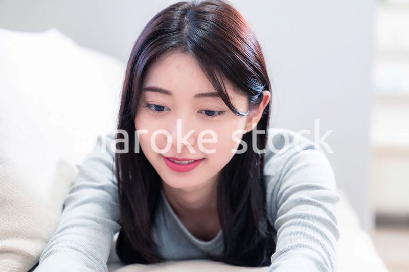 ソファでリラックスをしてスマホを使う若い女性